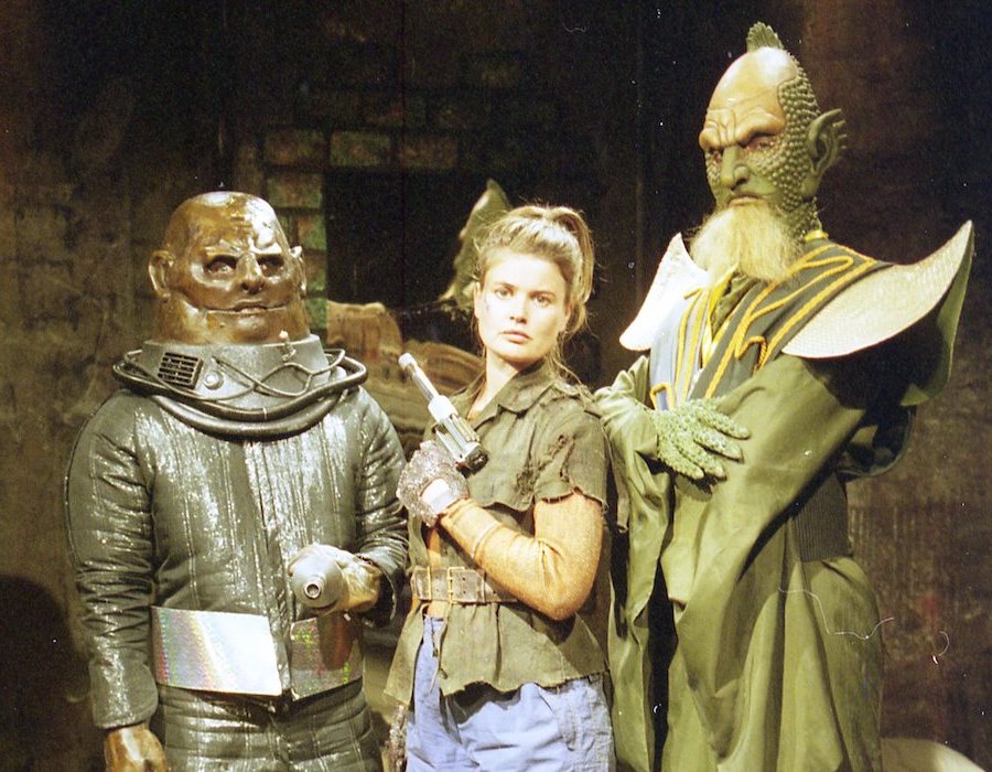 A still from Mindgame depicting three characters (one Human, one Draconian, one Sontaran) posing.